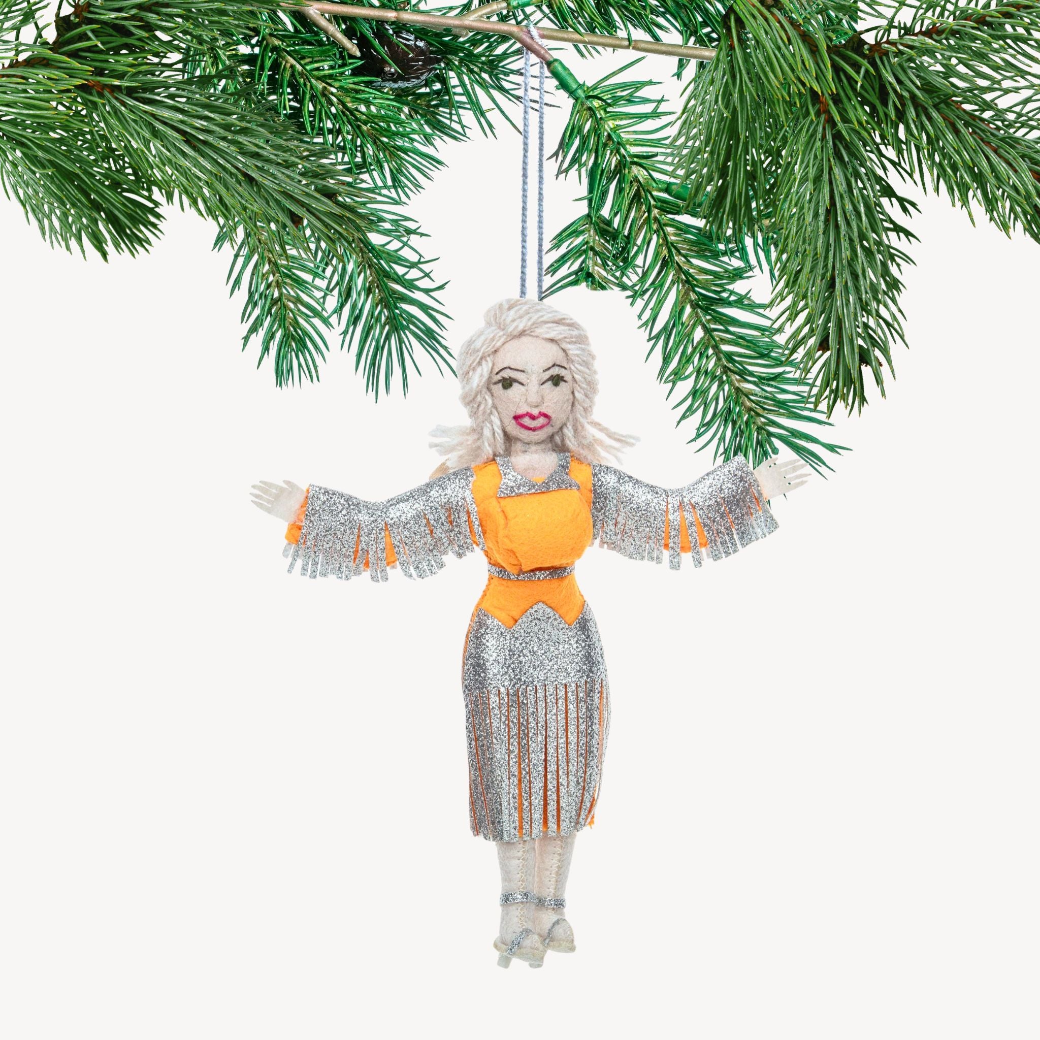 Decorative ornament of a woman in a silver dress with orange accents hanging from a branch.