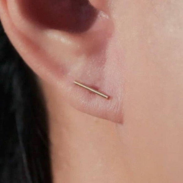 Gold bar earring on a person's ear
