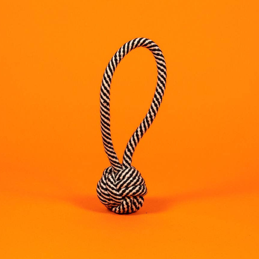 Black and white striped rope knot toy on an orange background