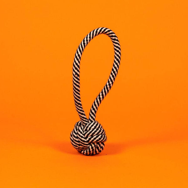 Black and white striped rope knot toy on an orange background