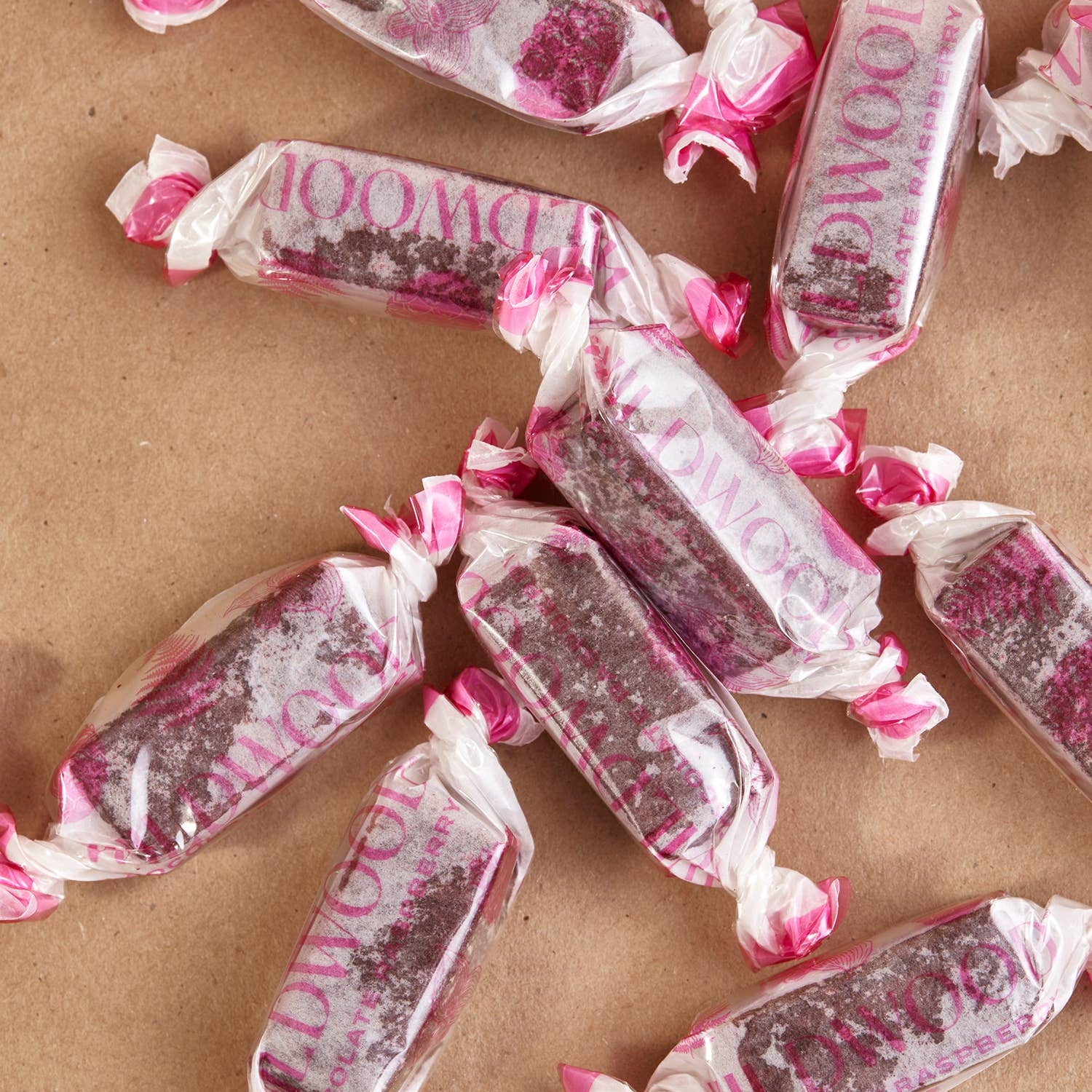 Pink and white wrapped candies on a brown surface