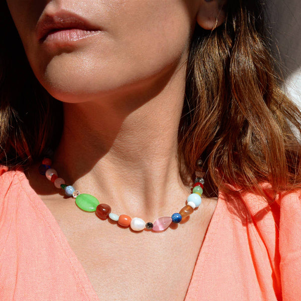 Close-up of a woman wearing a colorful beaded necklace with a blurred background
