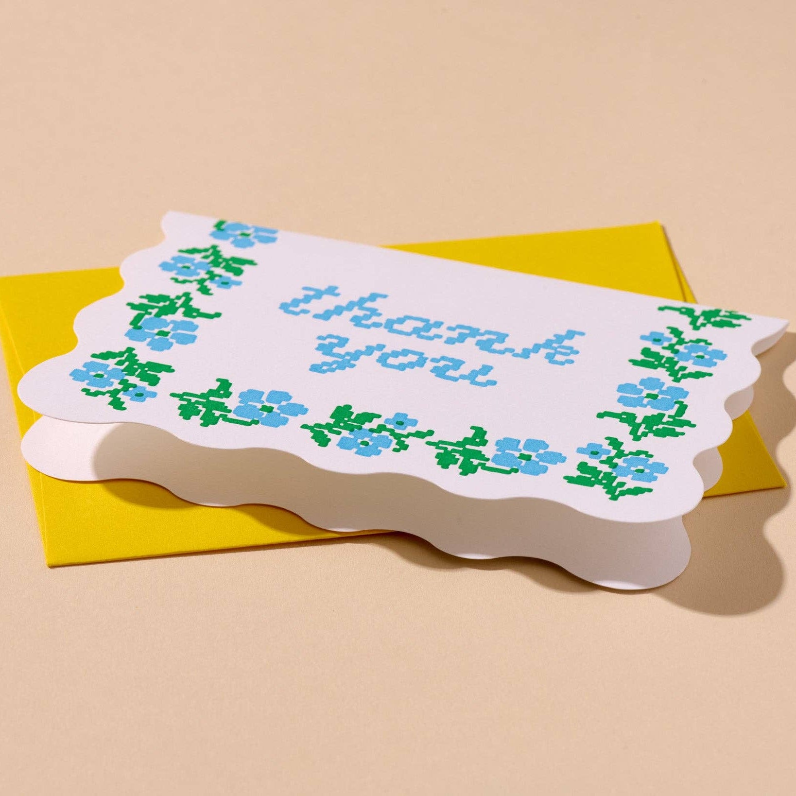 Greeting card with 'thank you' text and floral design on a beige background