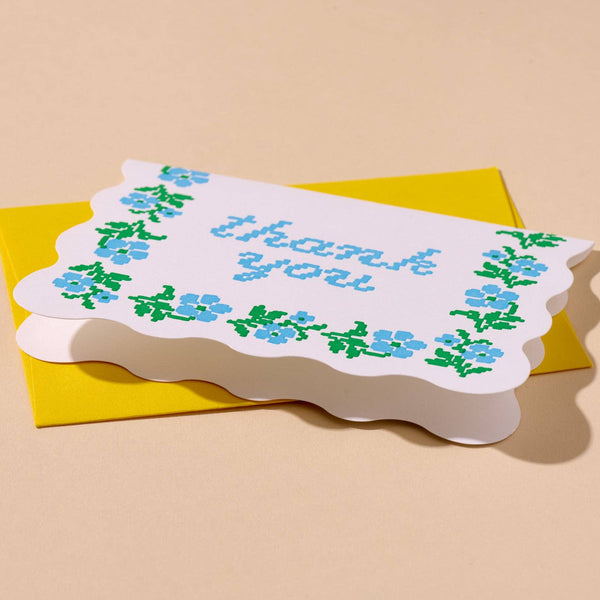 Greeting card with 'thank you' text and floral design on a beige background