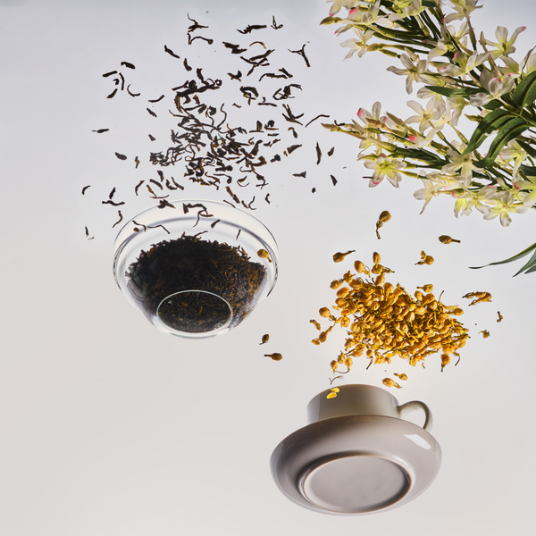 Tea leaves, flowers, and a teacup on a light gray background