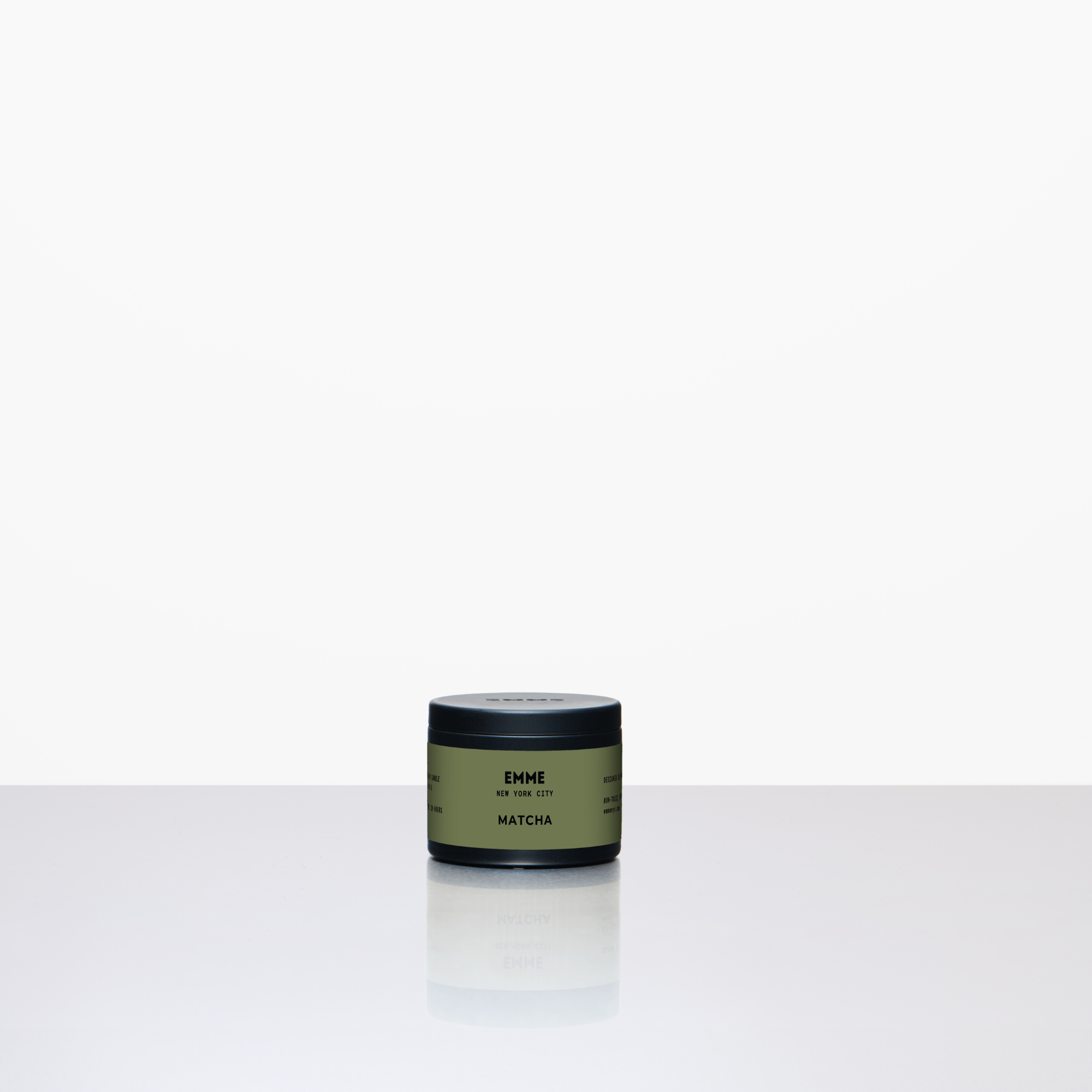 Green candle container labeled 'ENME' on a white background