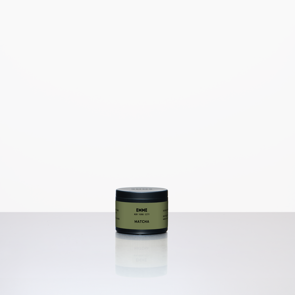 Green candle container labeled 'ENME' on a white background