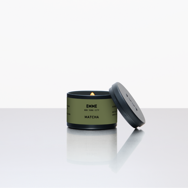 Green candle in a tin with a lid on a white background