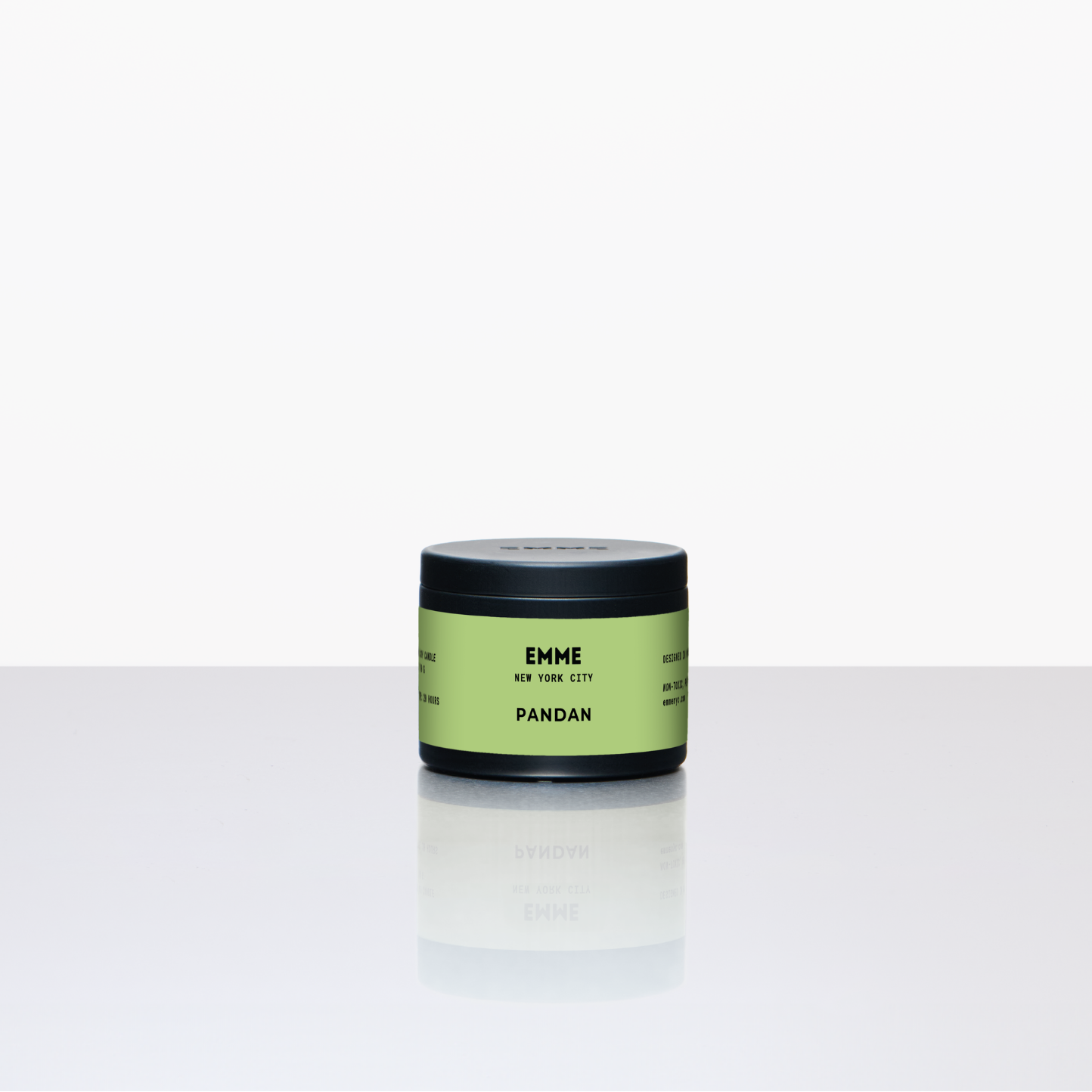 Green candle jar labeled 'EMME' on a white background