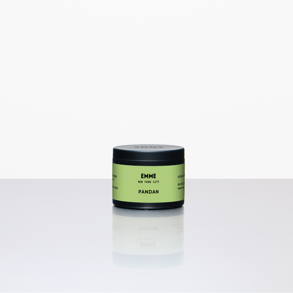 Green candle jar labeled 'EMME' on a white background