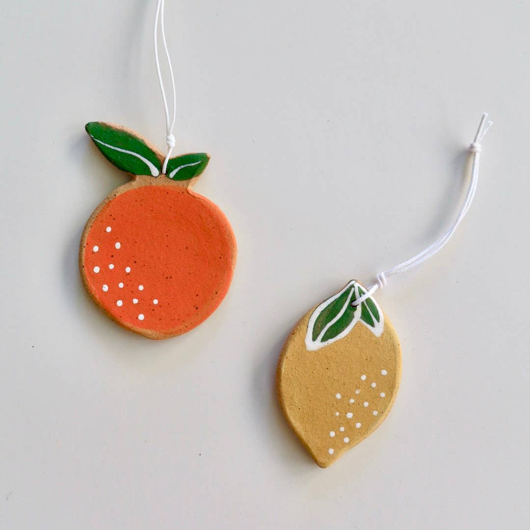Handmade ceramic orange and lemon ornaments with green stems, each with white hanging tags.