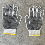 Pair of gloves with textured palm and yellow cuffs on a concrete surface