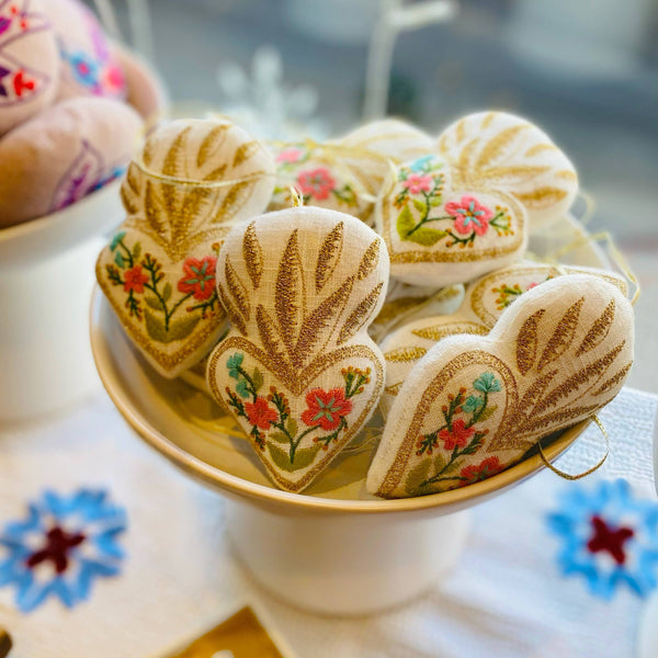 Decorative heart-shaped ornaments with floral designs on a white plate.
