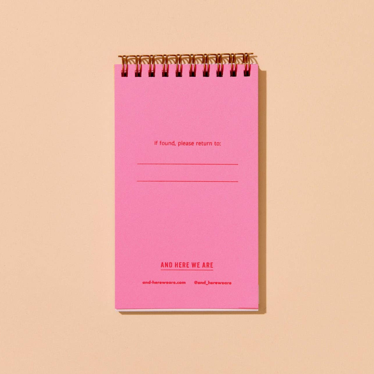 Pink page within spiral-bound notebook that says "if found, please return to:" on a beige background