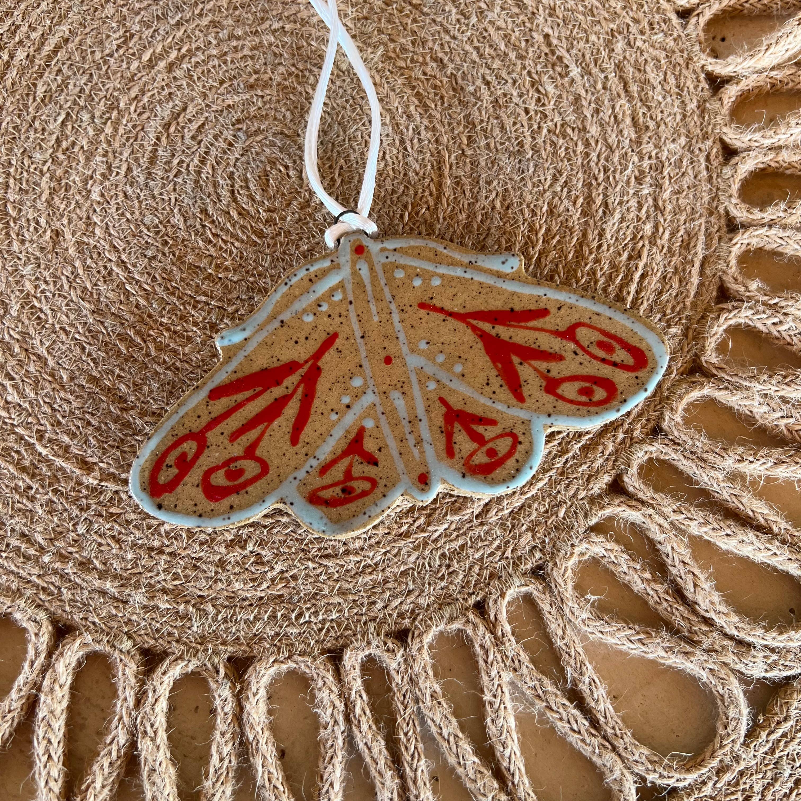 Colorful floral moth ceramic ornament by Tough Kitty Designs, featuring intricate flower patterns on a decorative ceramic surface.