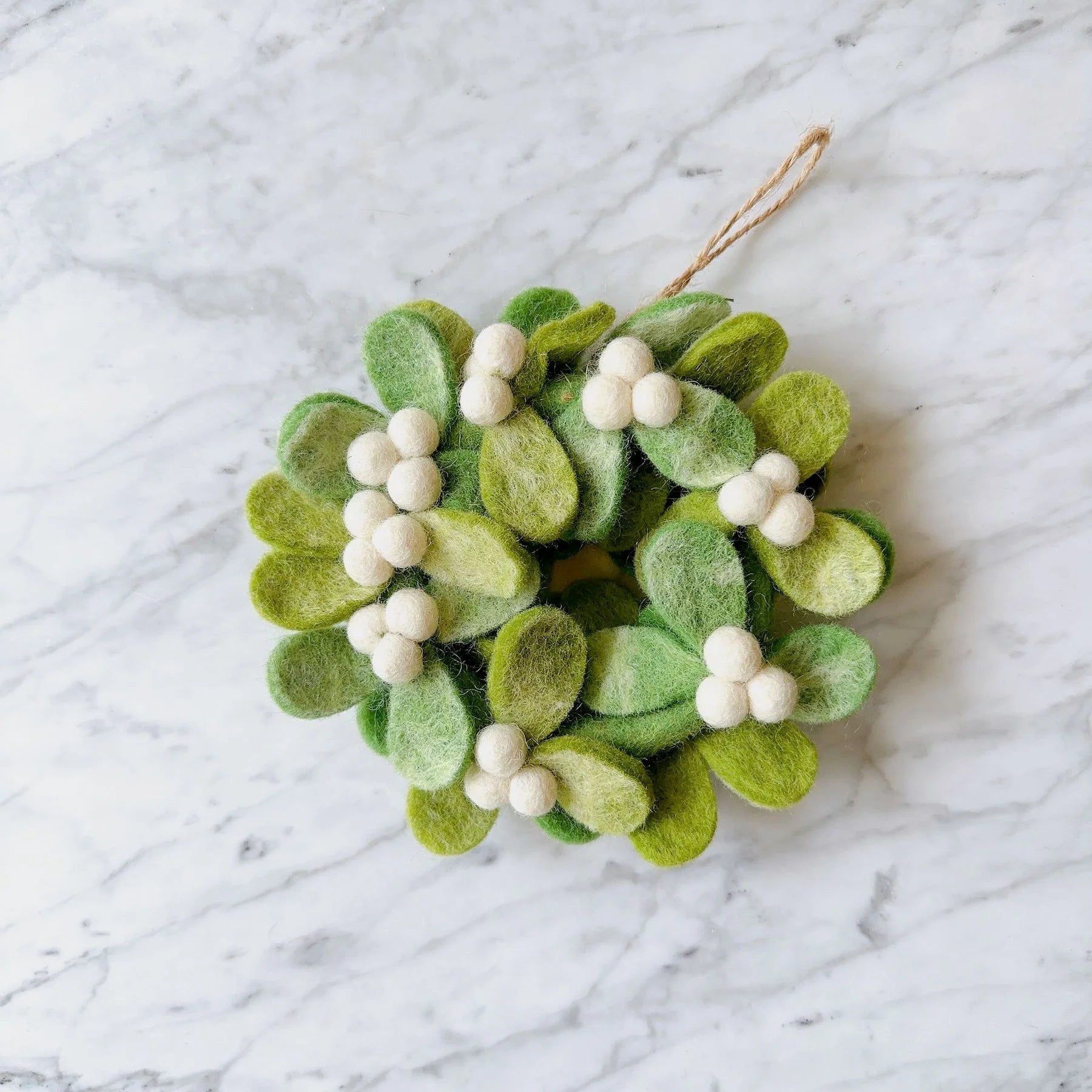 A felt mini mistletoe wreath ornament with green and white colors, featuring white beads and hanging from a string.