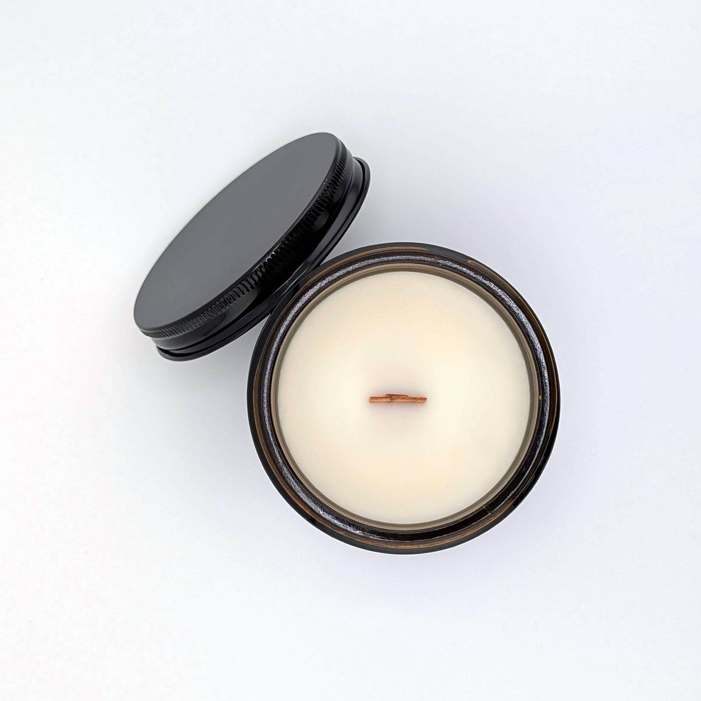 Candle in a tin with a black lid on a white background