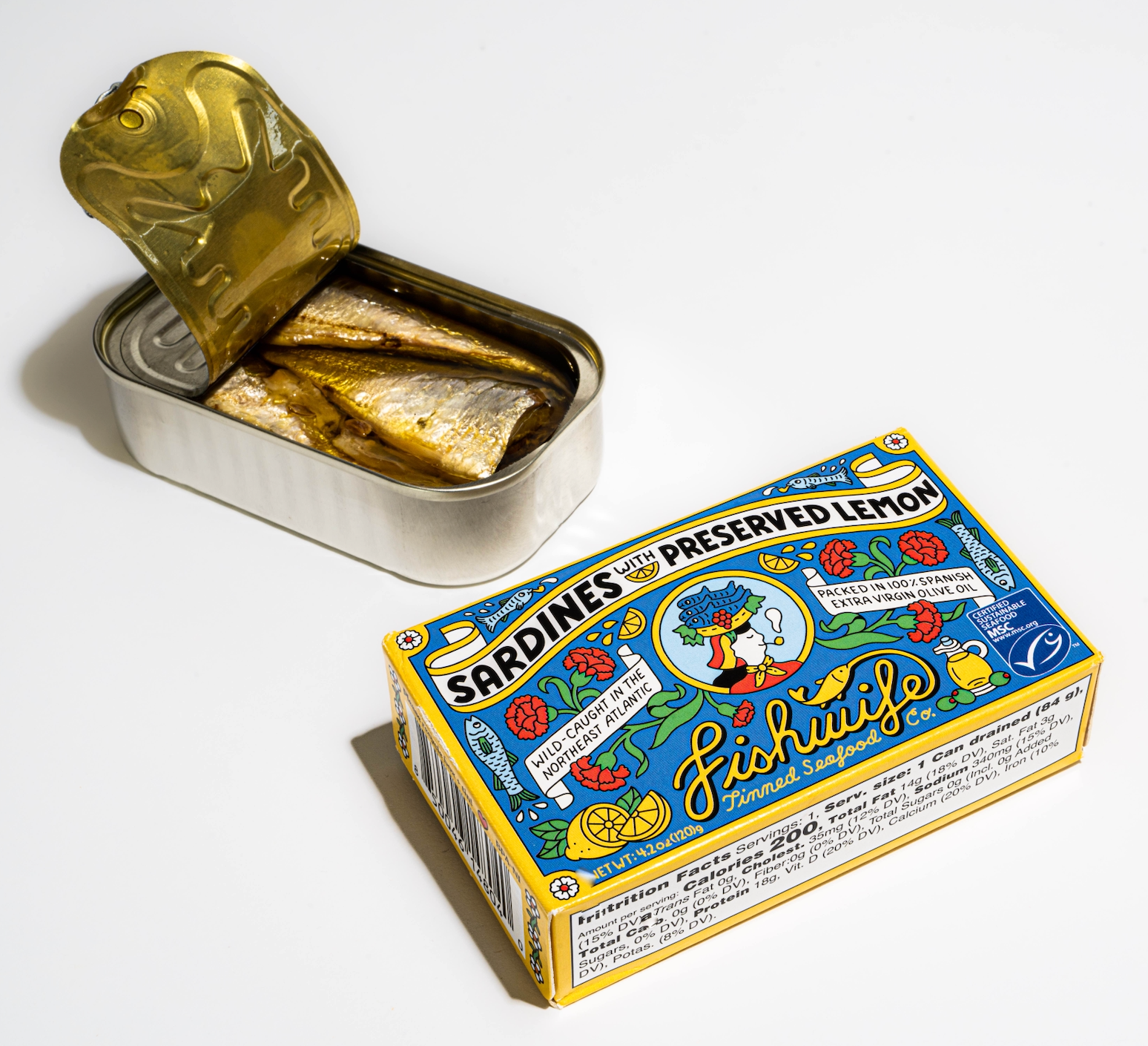 Open can of sardines next to its colorful packaging on a white background