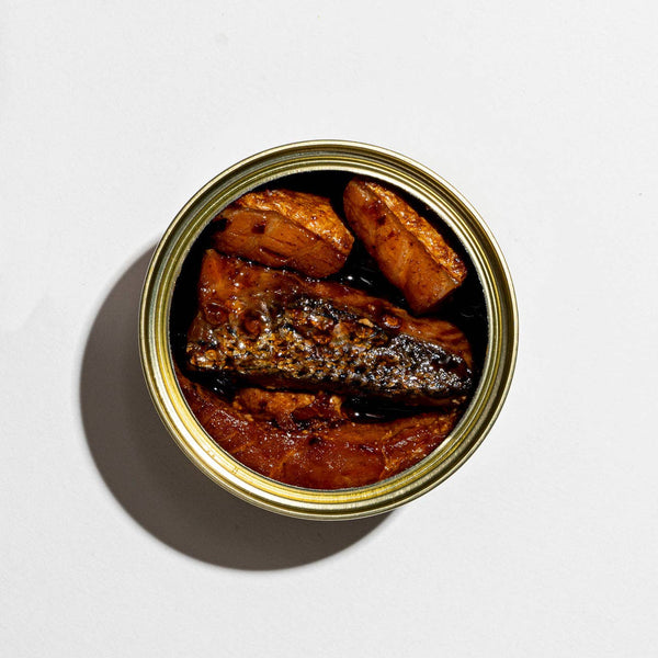 An open can of tinned fish on a white background.
