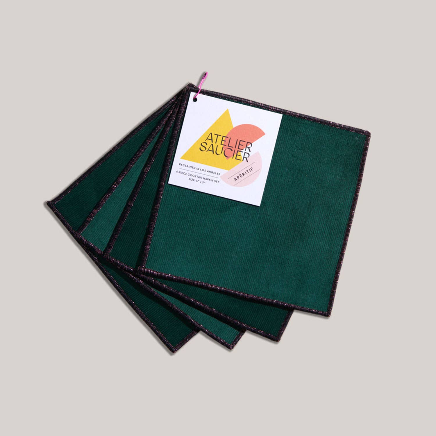 Set of green fabric cocktail napkins with a brand label on a light gray background