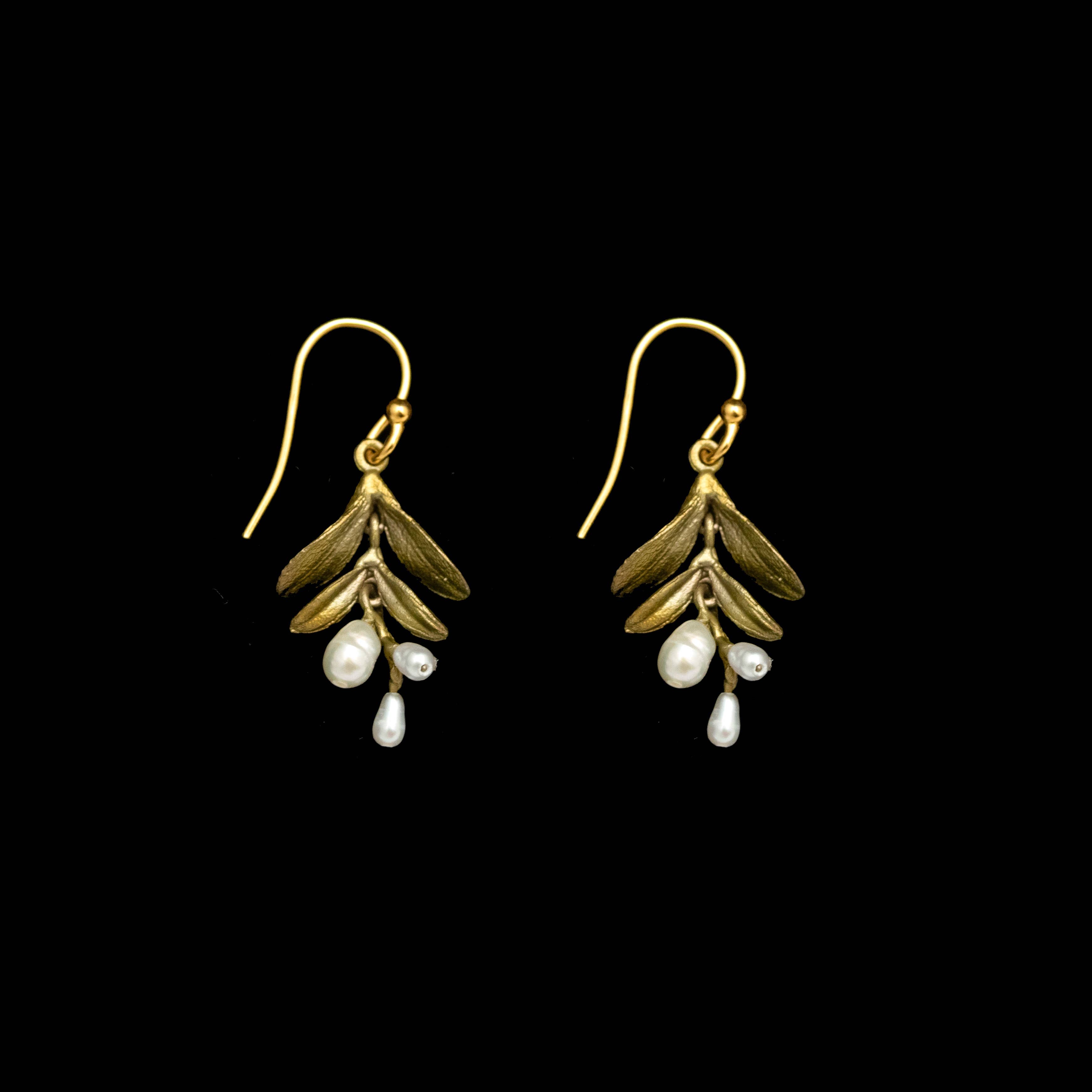 Gold leaf earrings with pearl drops on a plain background