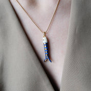 Necklace with a fish-shaped pendant worn by a person in a neutral setting