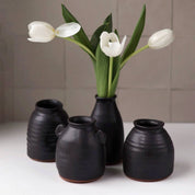 Set of black ceramic vases with white tulips on a neutral background