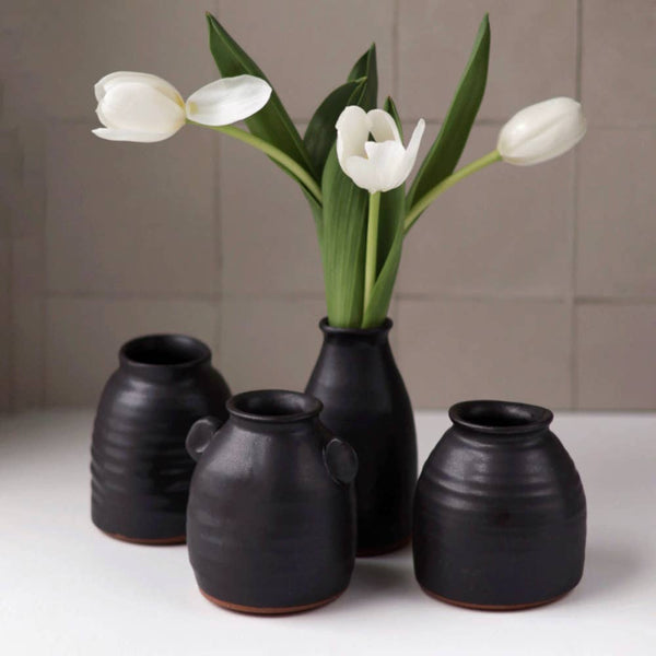 Set of black ceramic vases with white tulips on a neutral background