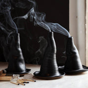 Black incense burners with smoke on a wooden surface