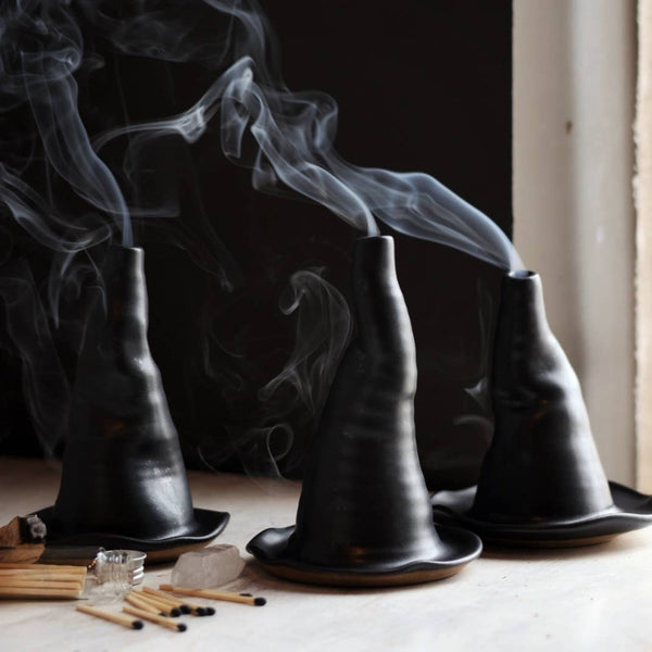 Black incense burners with smoke on a wooden surface