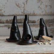 Three black ceramic cones on a rustic wooden surface with a neutral background.