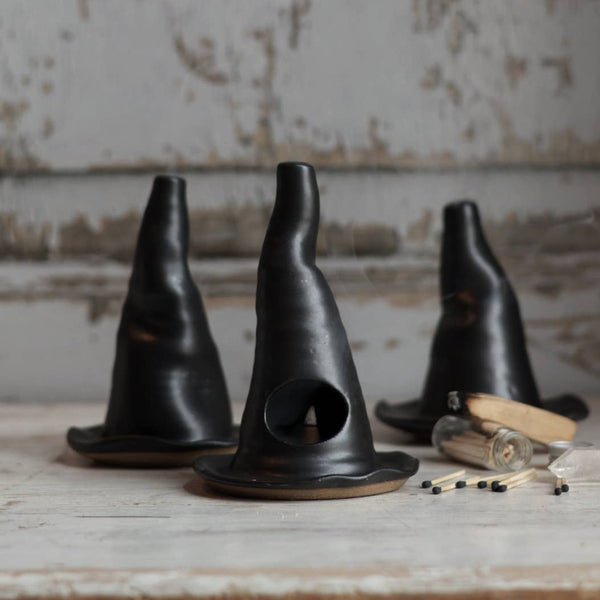 Three black ceramic cones on a rustic wooden surface with a neutral background.