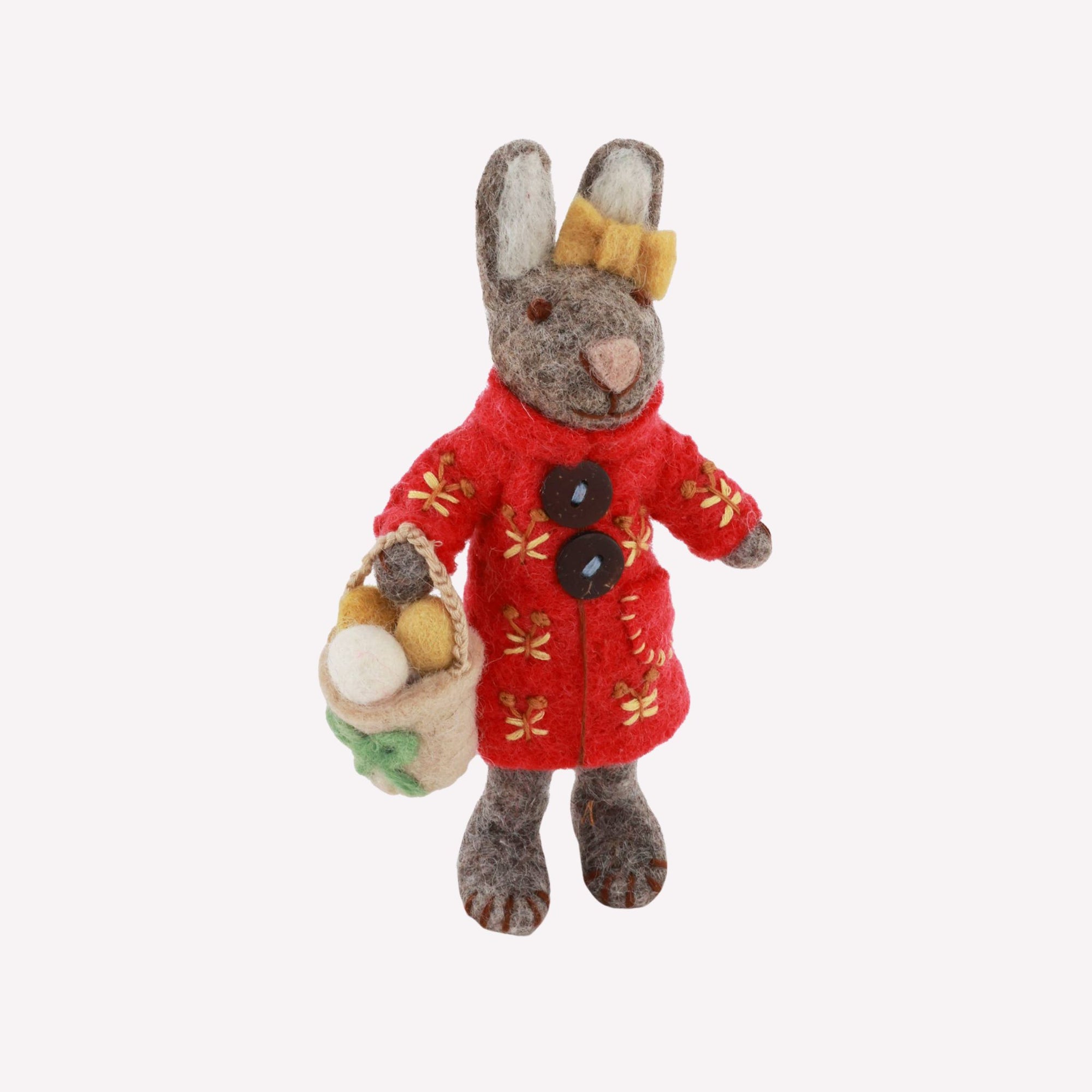 Stuffed toy rabbit in a red coat holding a basket of vegetables on a white background