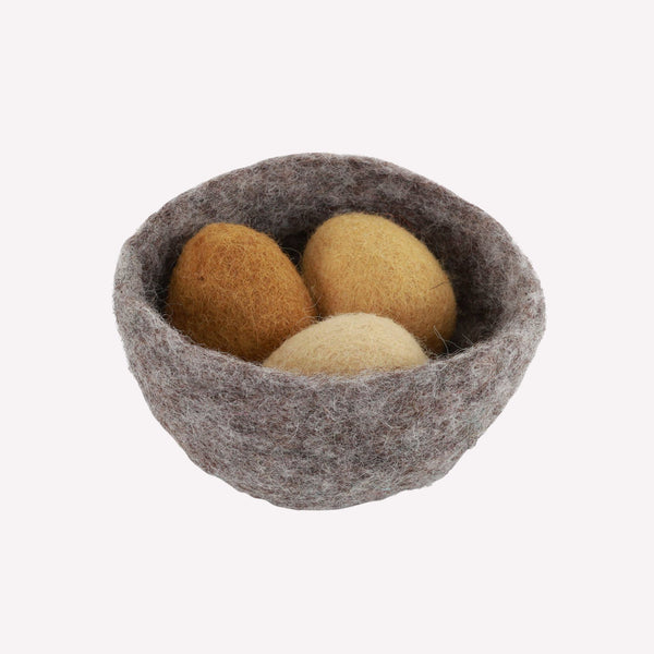 Felted wool eggs in a wool nest on a white background
