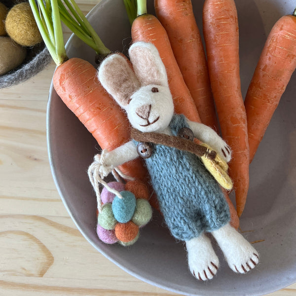 Plush toy rabbit with carrots on a wooden surface