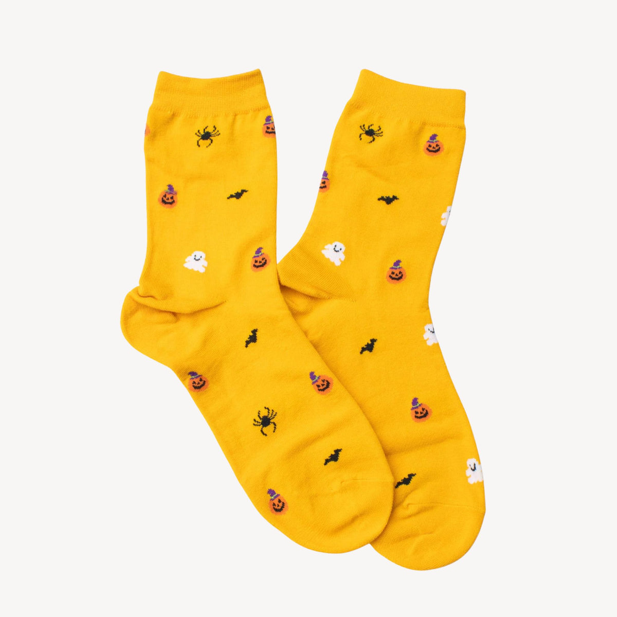 Bright yellow crew socks with a Halloween pattern featuring black bats, orange jack-o'-lanterns, white ghosts, and black spiders, laid flat on a white background.