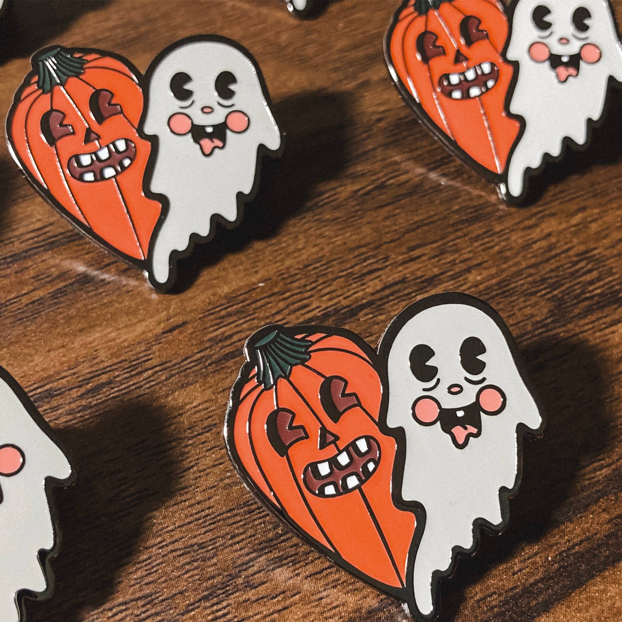 Halloween-themed pins with ghosts and pumpkins on a wooden surface.