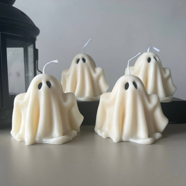 Ghost-shaped candles on a table with a lantern in the background