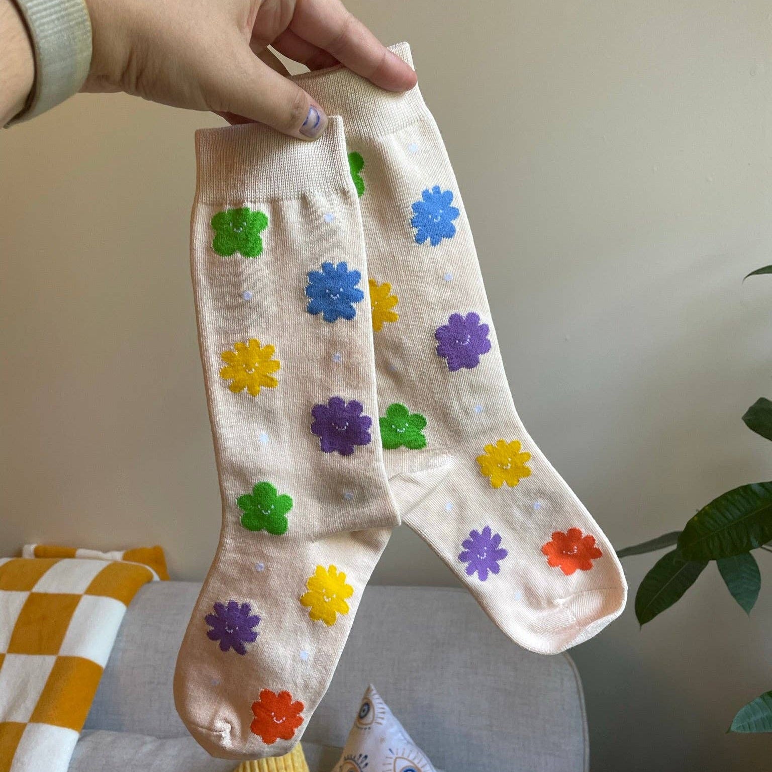 White sock with colorful flower patterns held by a hand against a neutral background