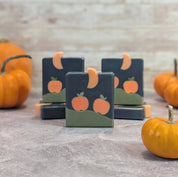 Bar soaps with pumpkin design on a stone surface with pumpkins in the background