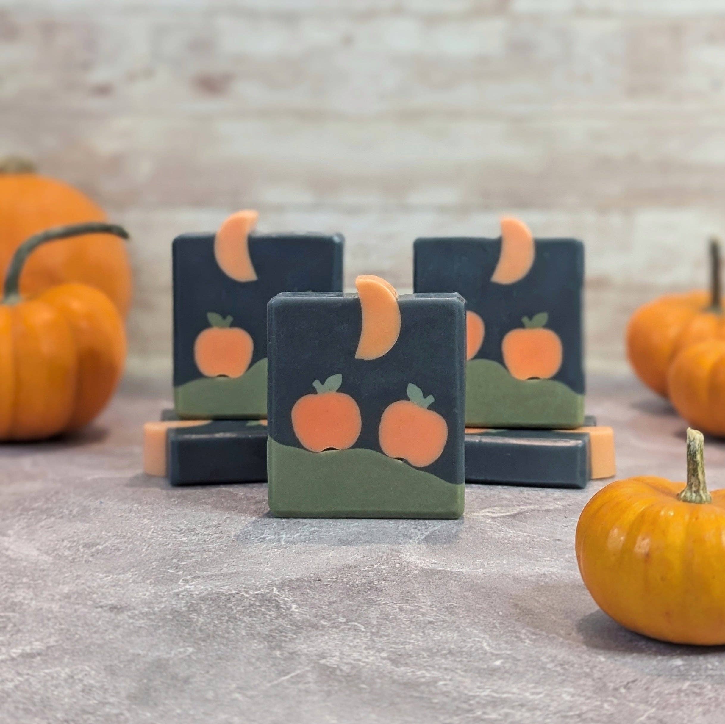 Bar soaps with pumpkin design on a stone surface with pumpkins in the background