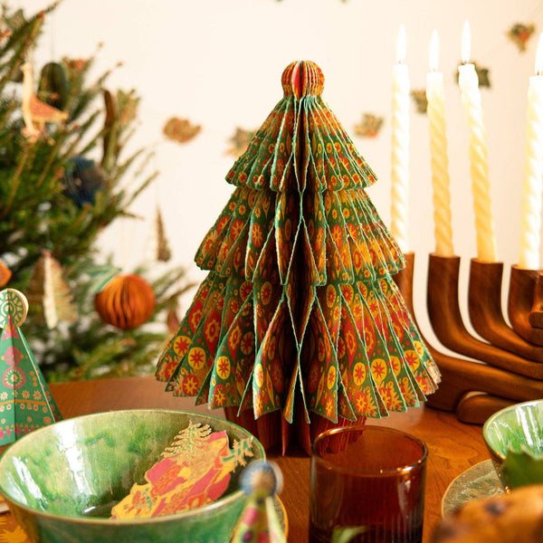 Decorative paper Christmas tree on a table with festive decorations.