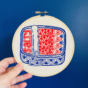 Embroidery hoop with red and blue fish pattern on a blue background