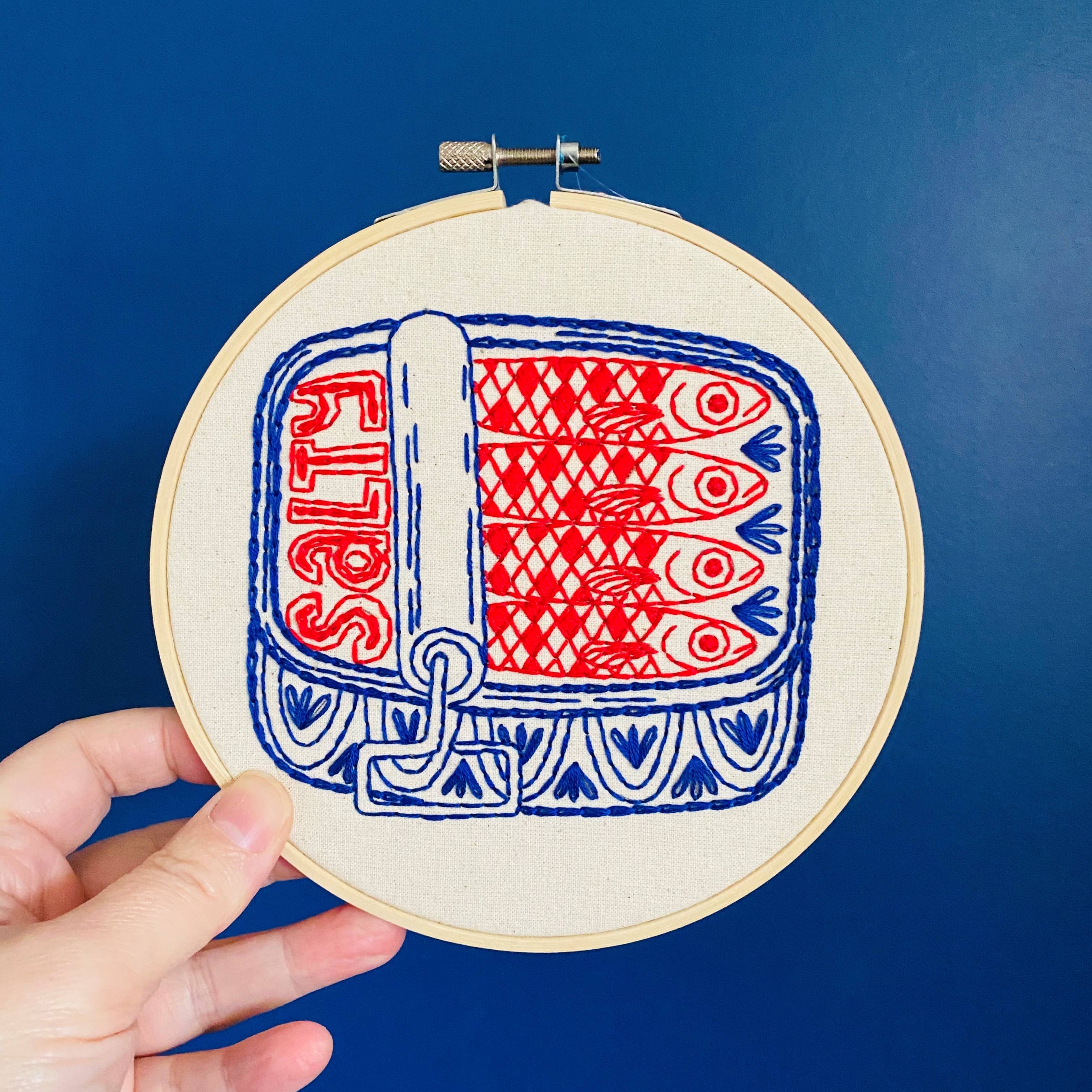 Embroidery hoop with red and blue fish pattern on a blue background