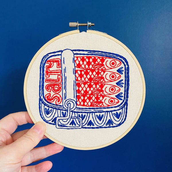 Embroidery hoop with red and blue fish pattern on a blue background