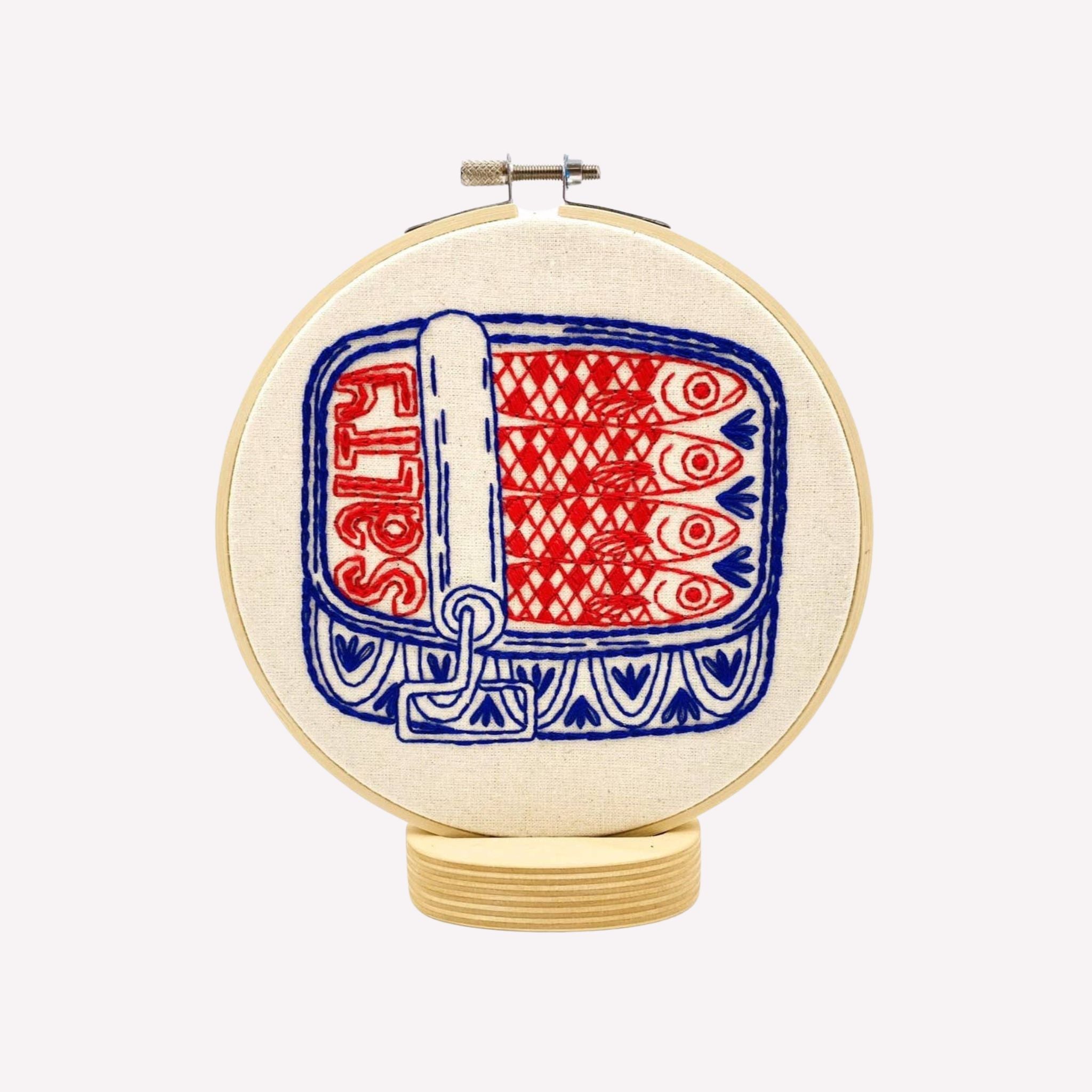 Embroidery hoop with a red and blue sardine pattern on a white background
