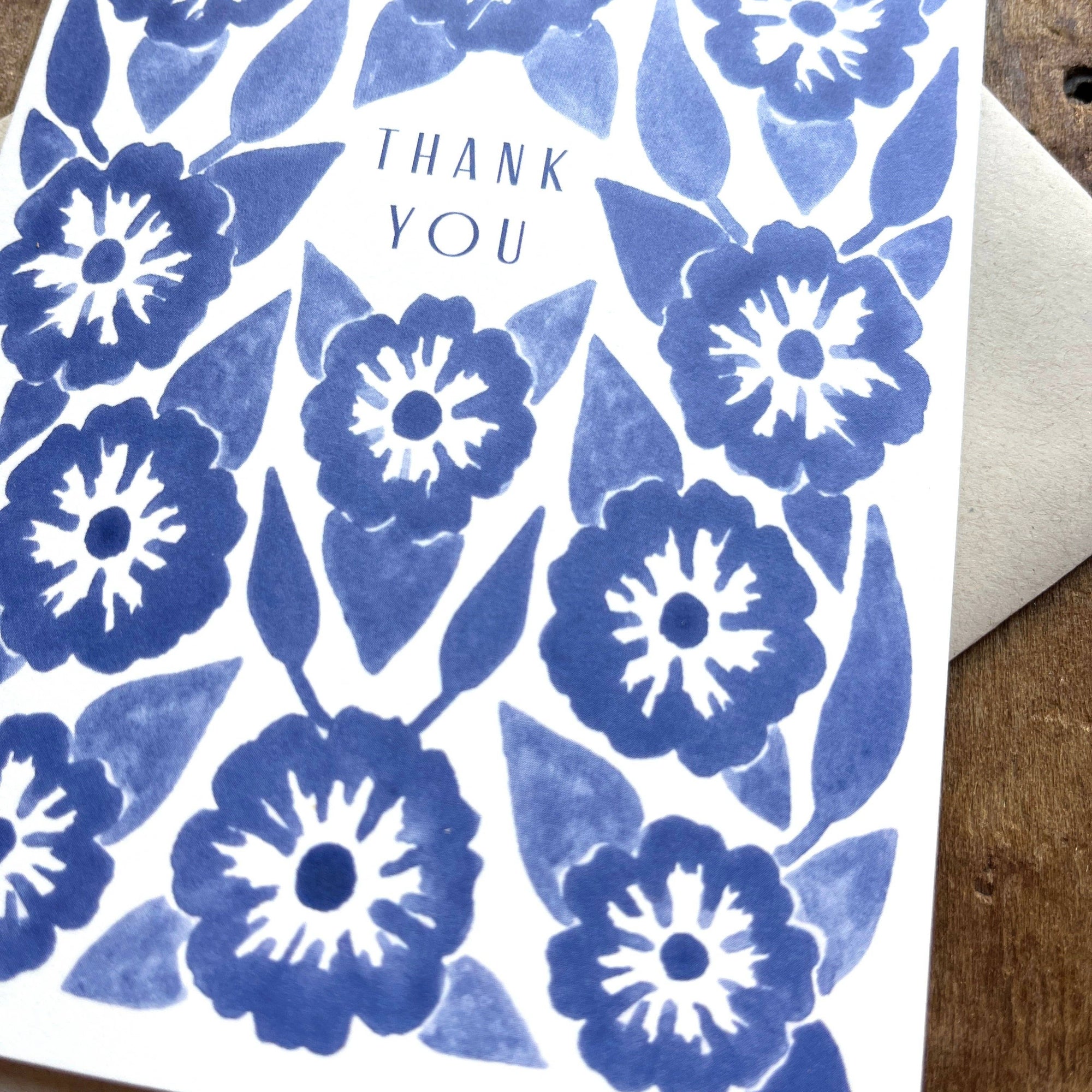 Greeting card with blue floral pattern and 'Thank You' text on a wooden surface