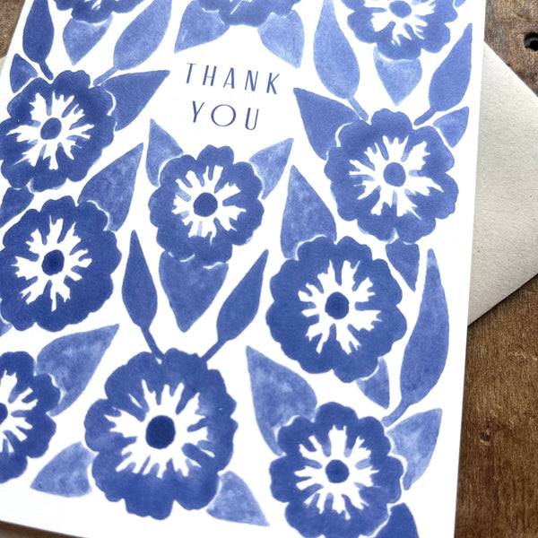 Greeting card with blue floral pattern and 'Thank You' text on a wooden surface