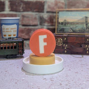 Bar Soap with 'F' subway train "logo" on a white base against a brick wall.