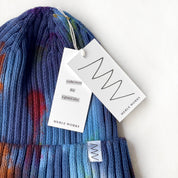 A blue hat with two white paper tags, laying against a white background.